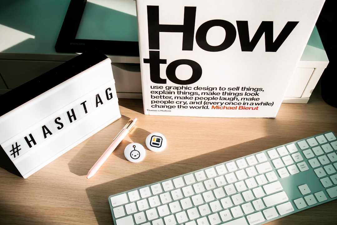 Modern desk with a lightbox showing #HASHTAG and graphic design book.